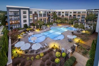 A swimming pool surrounded by a patio with chairs and umbrellas.
